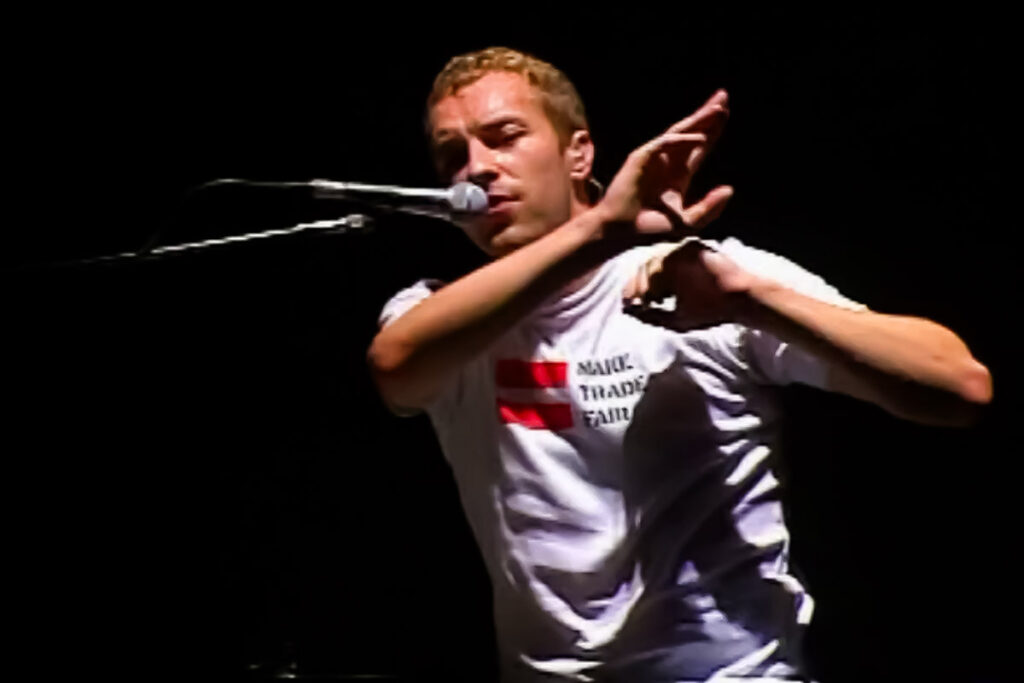 Chris Martin wearing a "make trade fair" t-shirt performing on stage during the Rush of Blood to the Head era